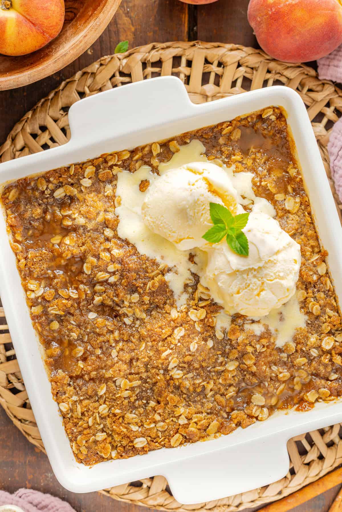 Warmly spiced fresh peaches are topped with a crumble topping in this Peach Crisp recipe. Serve with ice cream for a quick & easy dessert! Overhead view of a baking dish of peach crisp
