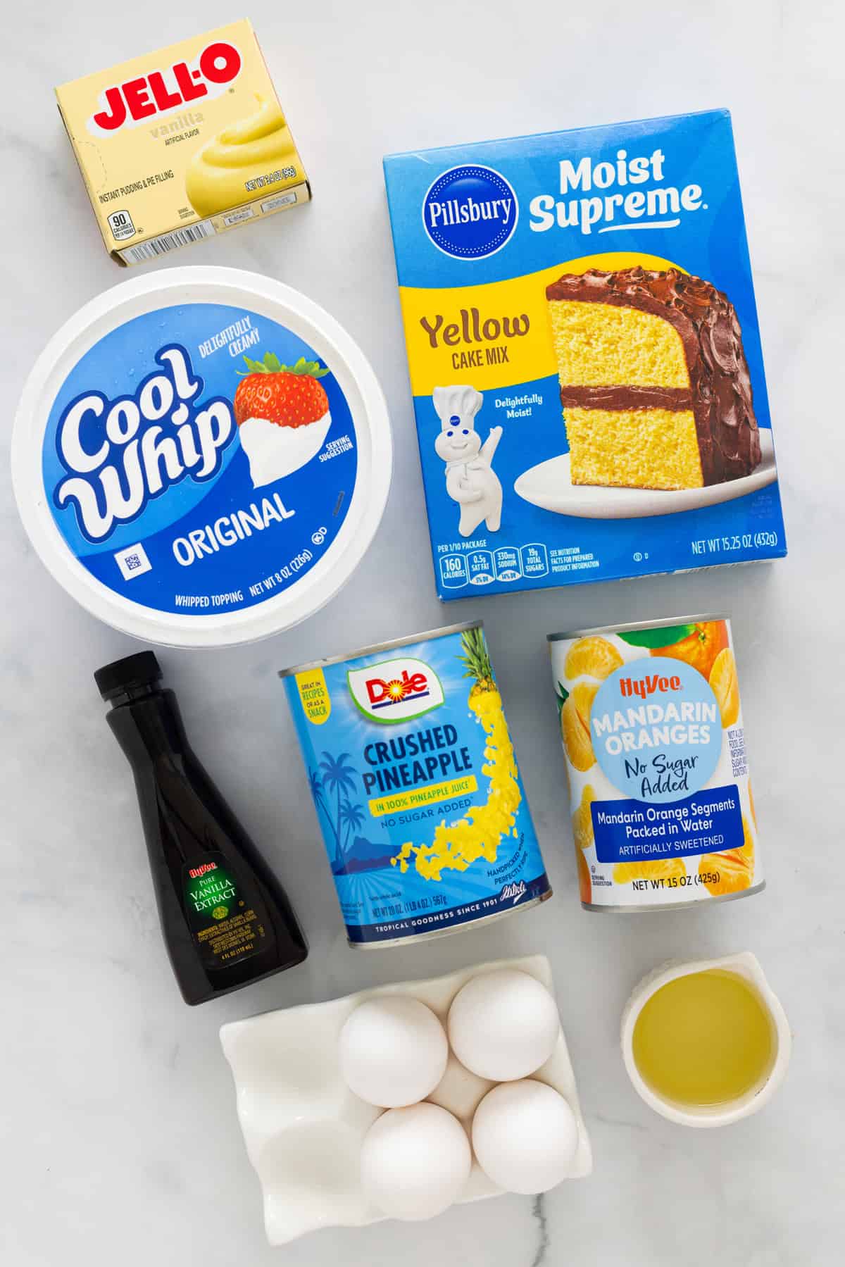This Pig Pickin' Cake is made with box cake mix combined with mandarin oranges and a pineapple Cool Whip frosting. SO easy to make! Overhead view of ingredients needed to make pig pickin' cake