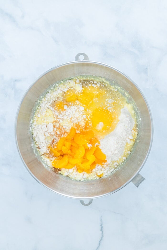 This Pig Pickin' Cake is made with box cake mix combined with mandarin oranges and a pineapple Cool Whip frosting. SO easy to make! Cake mix, eggs, and mandarin oranges in a bowl