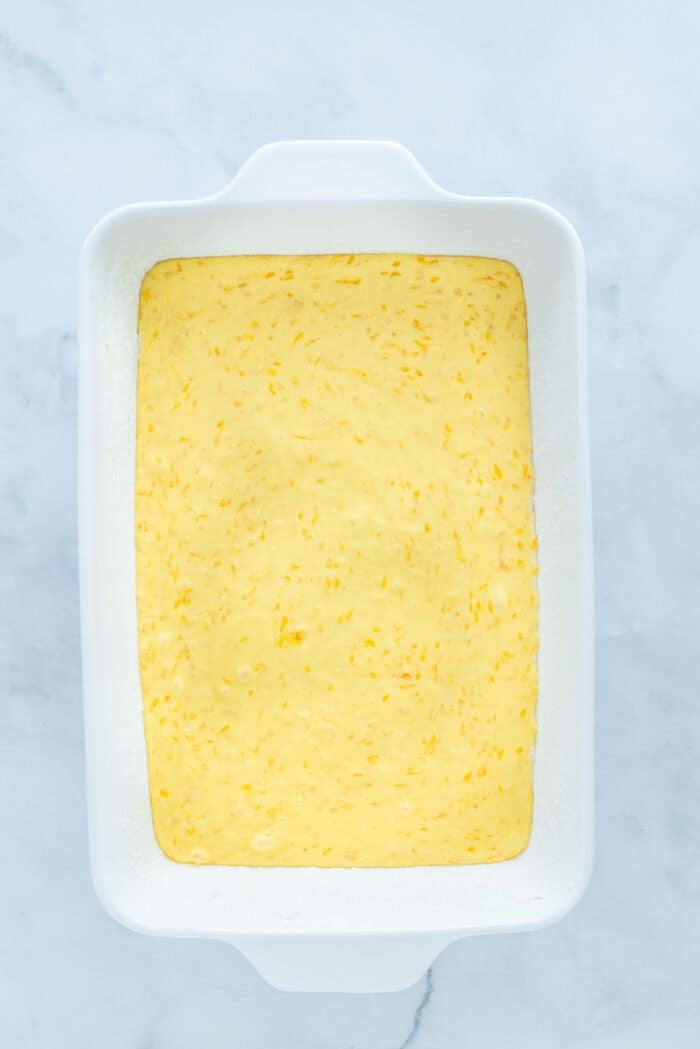 This Pig Pickin' Cake is made with box cake mix combined with mandarin oranges and a pineapple Cool Whip frosting. SO easy to make! Cake batter in a pan