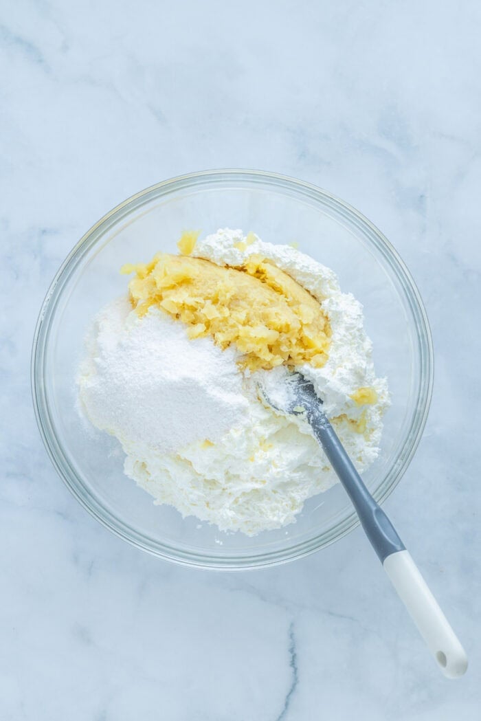 This Pig Pickin' Cake is made with box cake mix combined with mandarin oranges and a pineapple Cool Whip frosting. SO easy to make! Stirring pineapple into cool whip