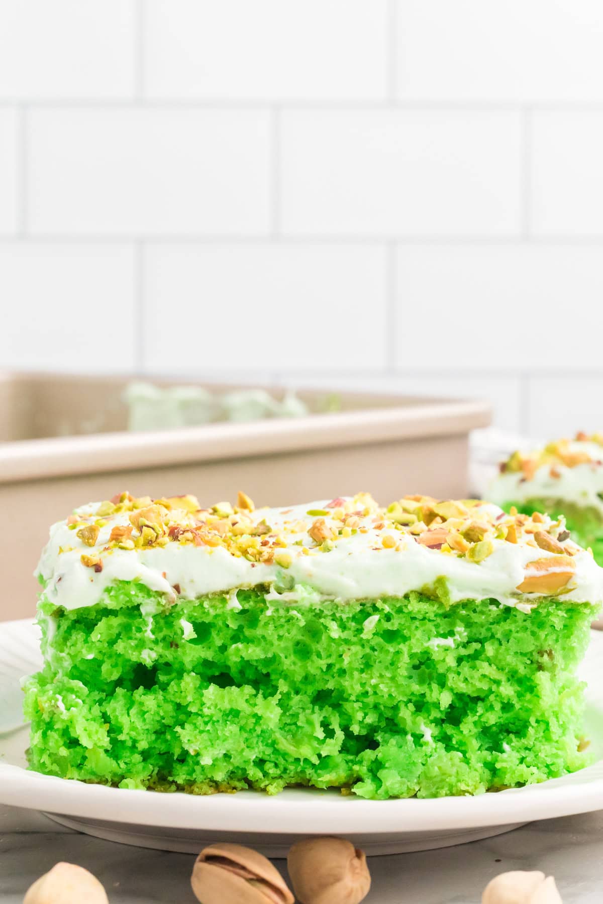 A slice of pistachio cake on a white plate