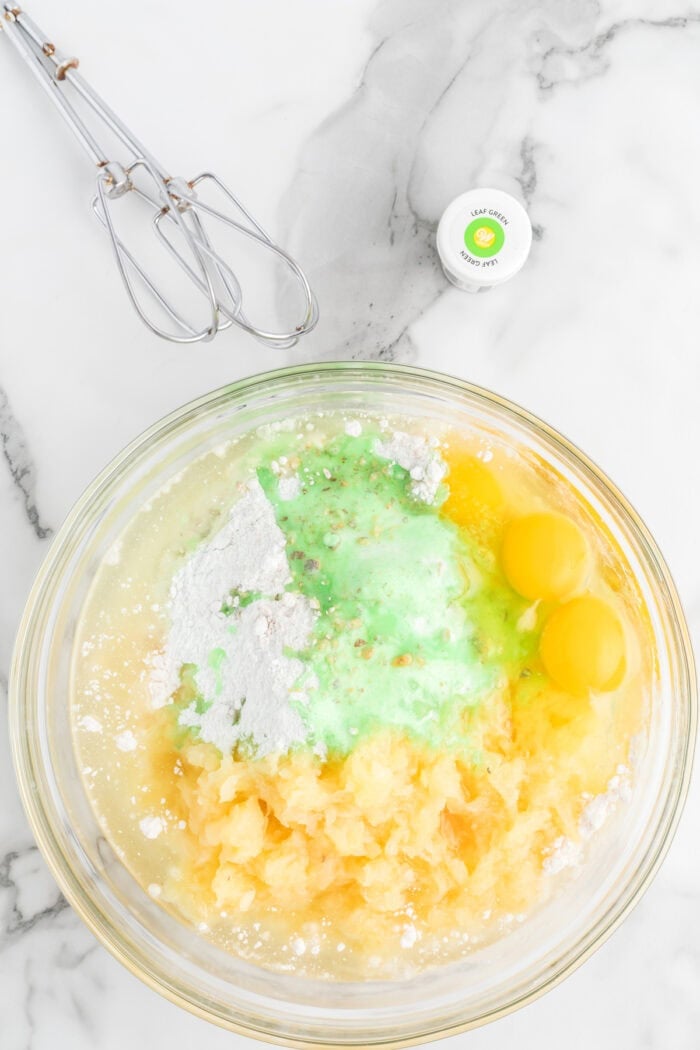 Cake mix, pistachio pudding mix, and pineapple in a bowl