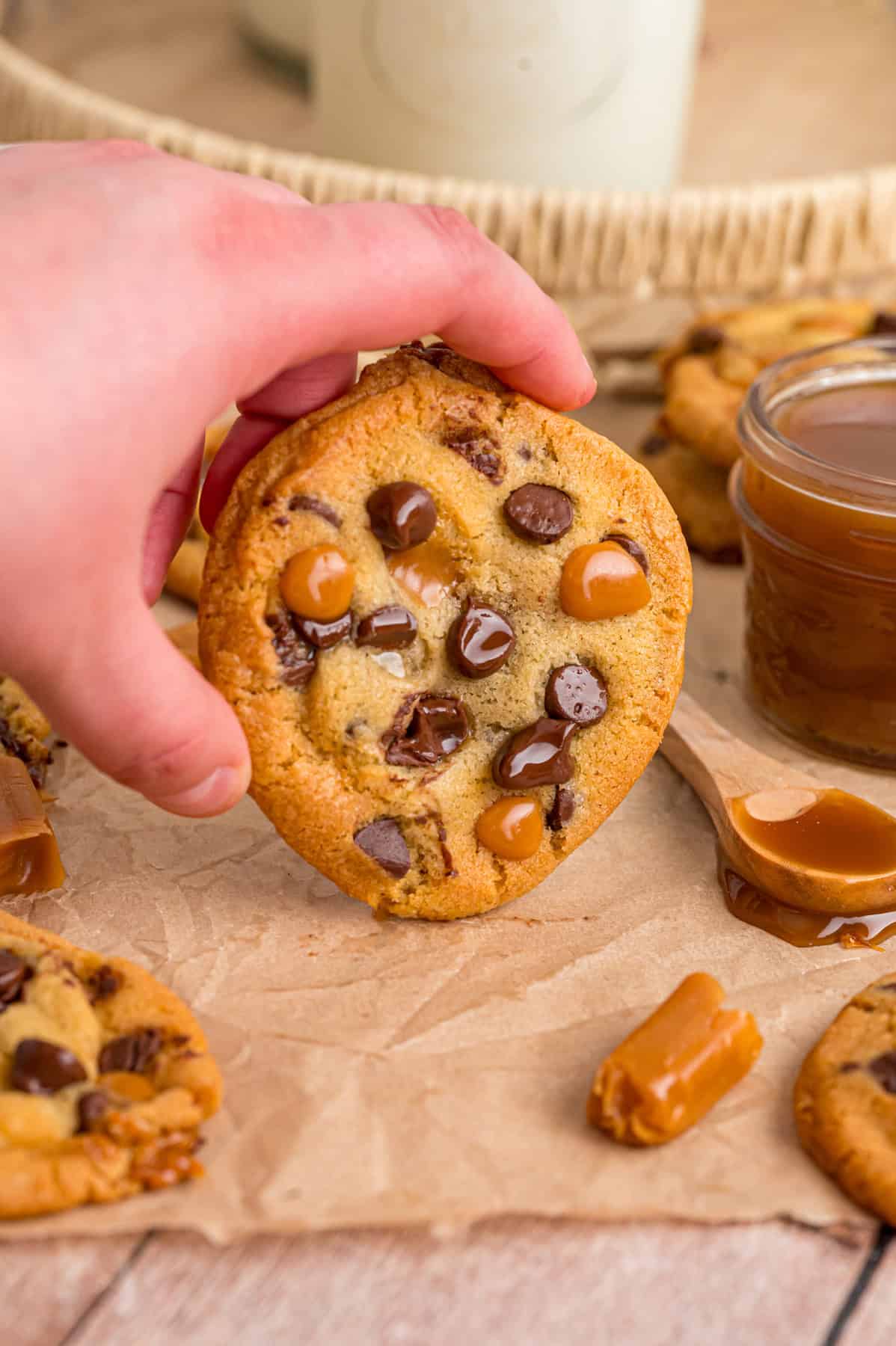 A hand holding a caramel chocolate chip cookie