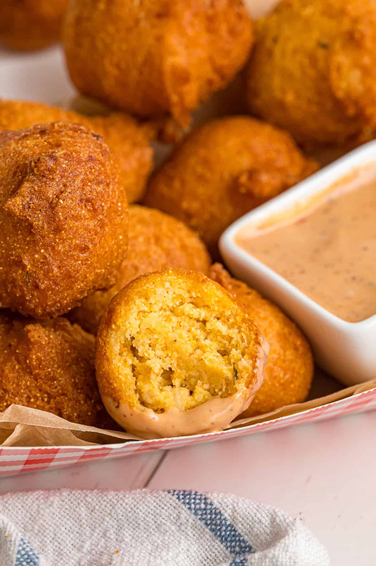 A basket of hush puppies, one with a bite missing