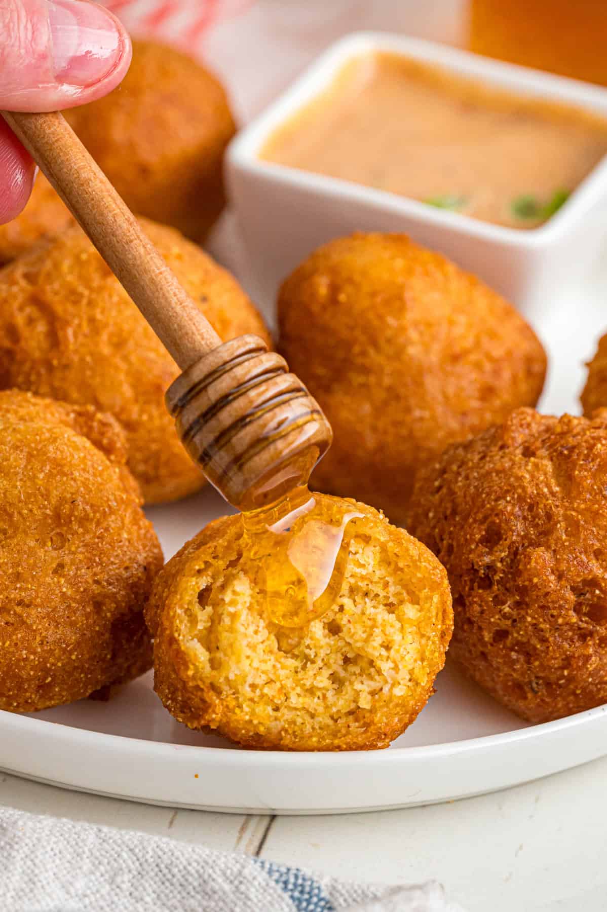 Drizzling honey over a hush puppy
