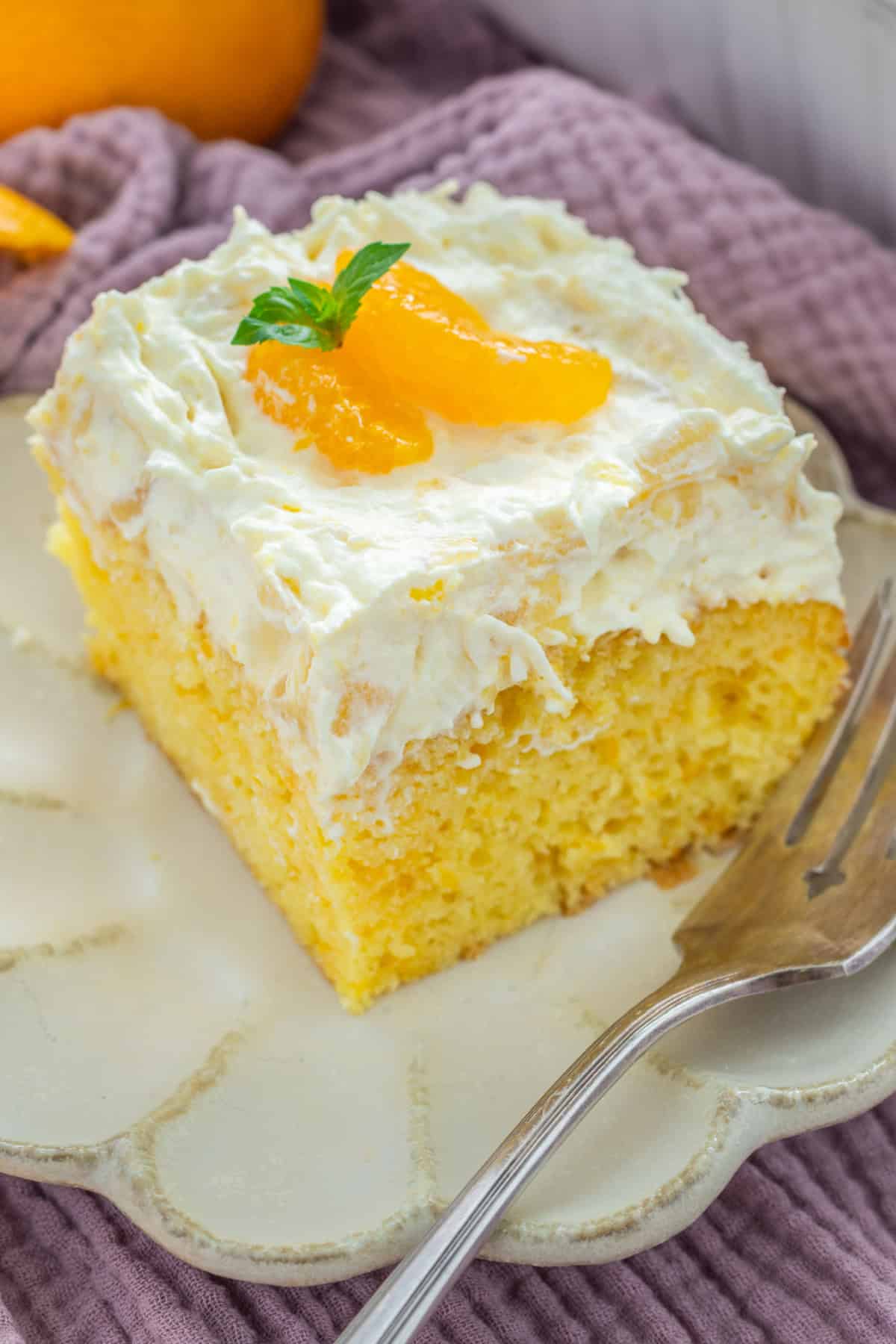 This Pig Pickin' Cake is made with box cake mix combined with mandarin oranges and a pineapple Cool Whip frosting. SO easy to make! Pig Pickin' Cake slice on a plate