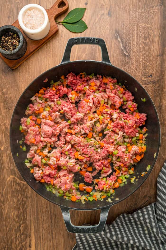Ground pork, beef, and veggies cooking in a skillet