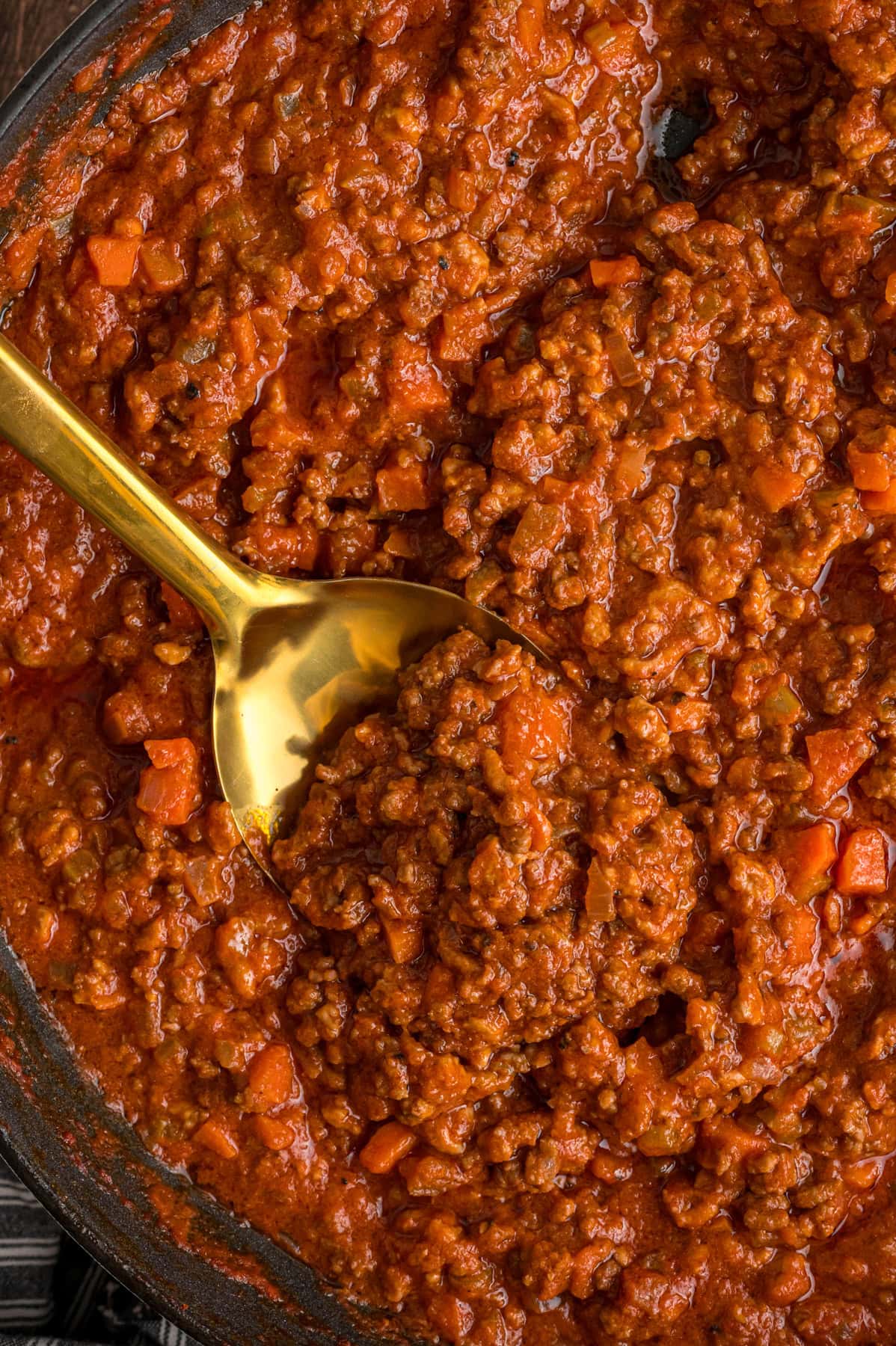 A spoon in a pan of bolognese sauce