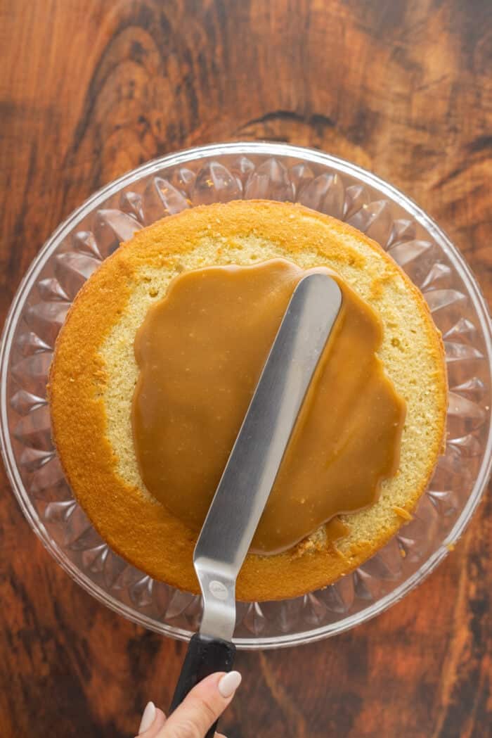 Spreading caramel frosting on a cake layer