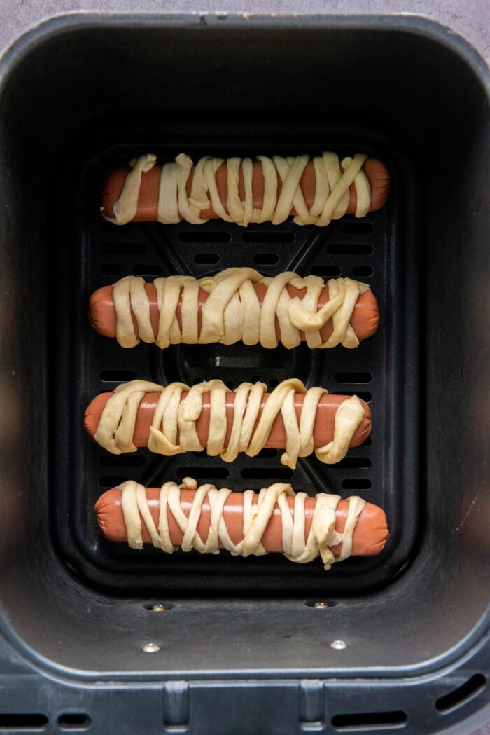 Hot dogs wrapped in crescent roll dough strips in the air fryer