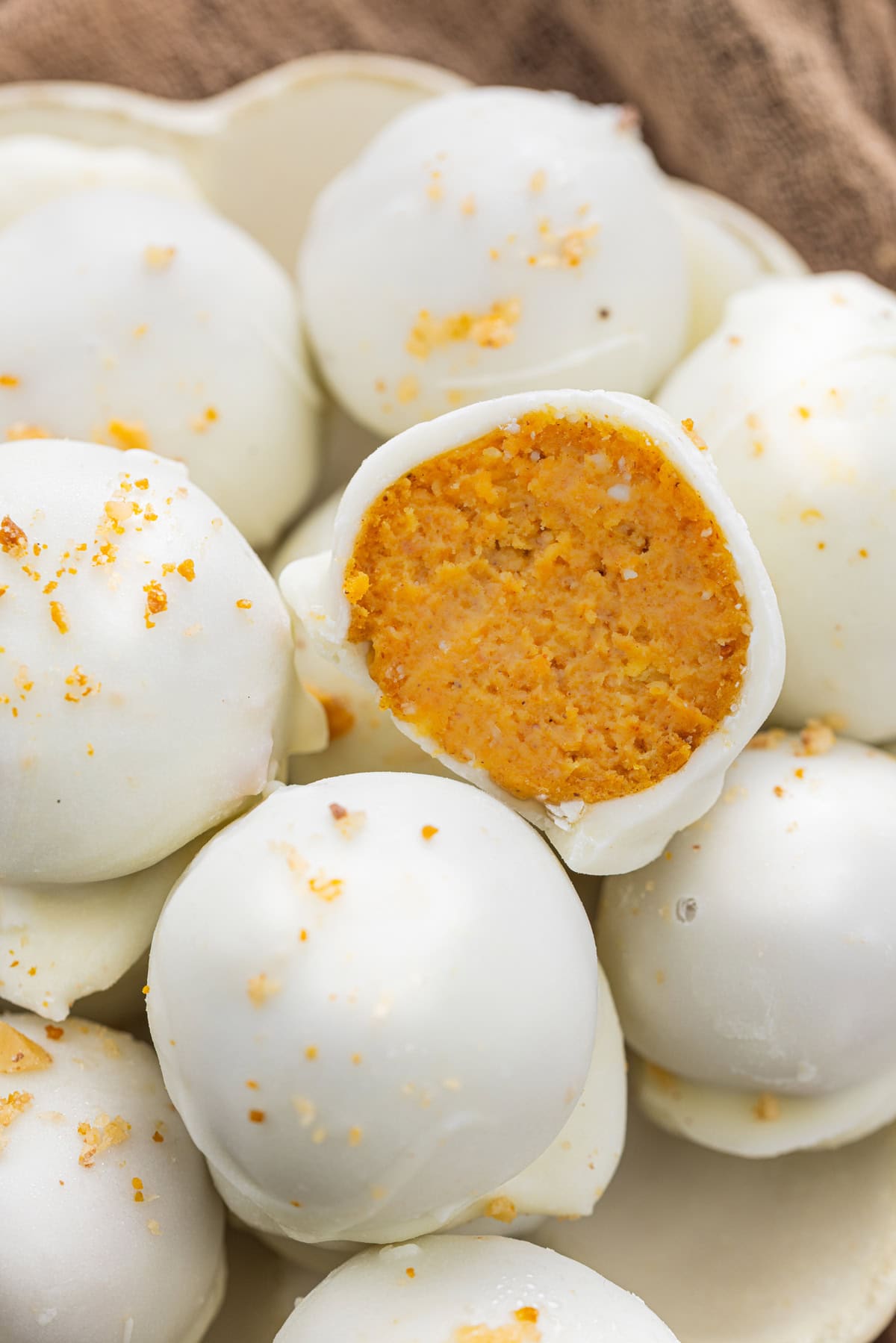 A plate of pumpkin truffles, one cut open to show the filling