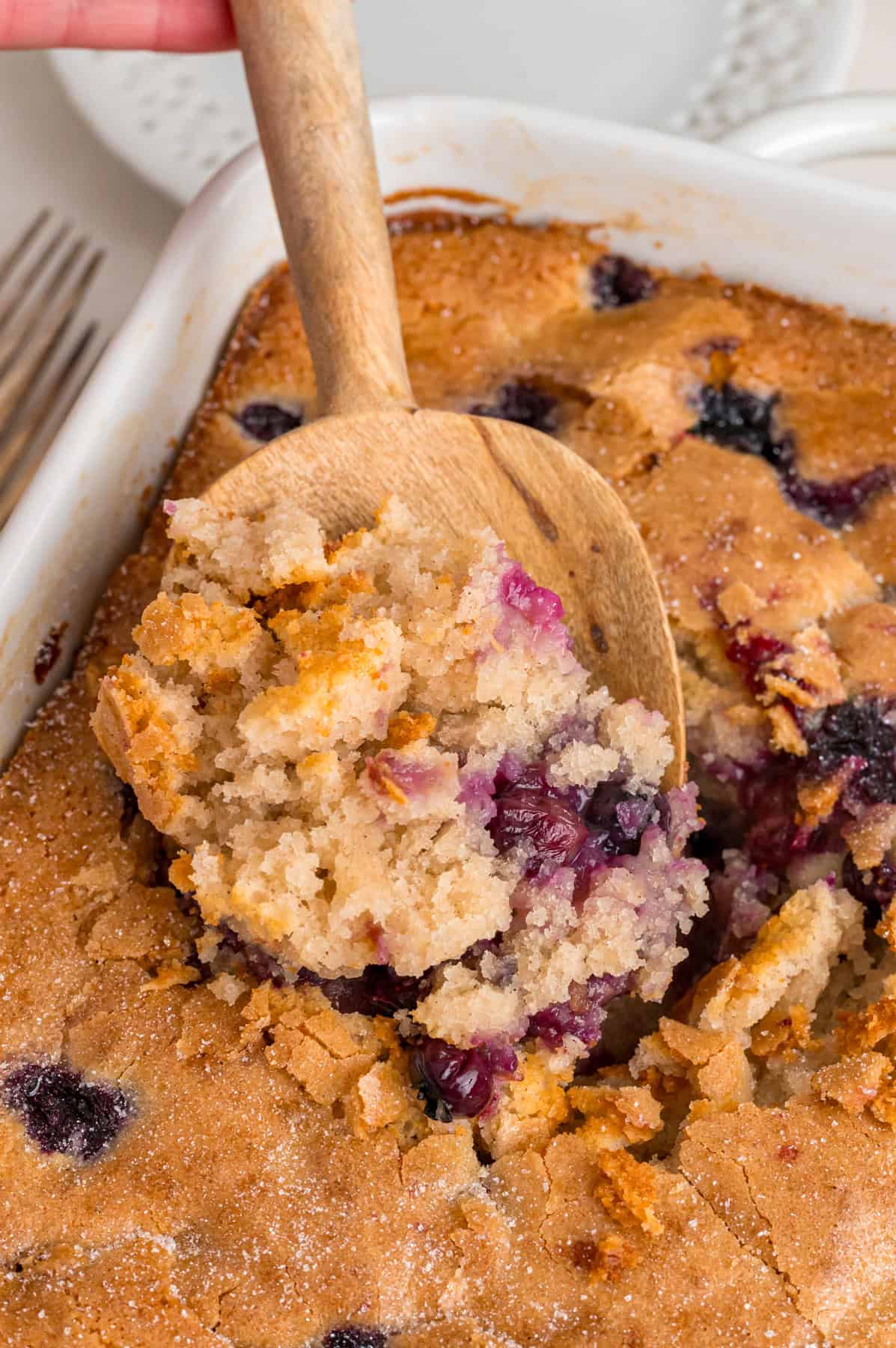 A wooden spoon serving blueberry cobbler