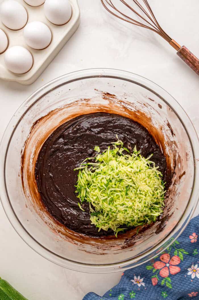 This Chocolate Zucchini Cake is rich, moist, and topped with an irresistible chocolate buttercream! It's a must-bake every summer! Stirring grated zucchini into chocolate cake batter