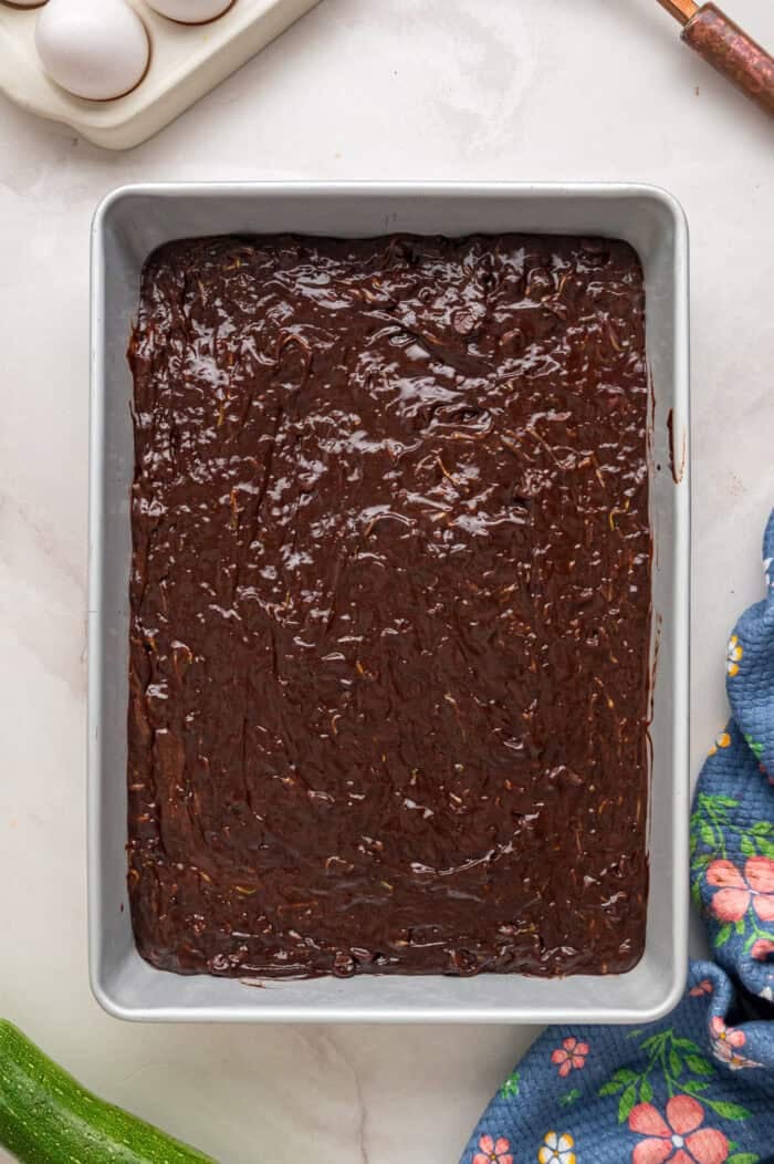 This Chocolate Zucchini Cake is rich, moist, and topped with an irresistible chocolate buttercream! It's a must-bake every summer! Chocolate cake batter in a pan