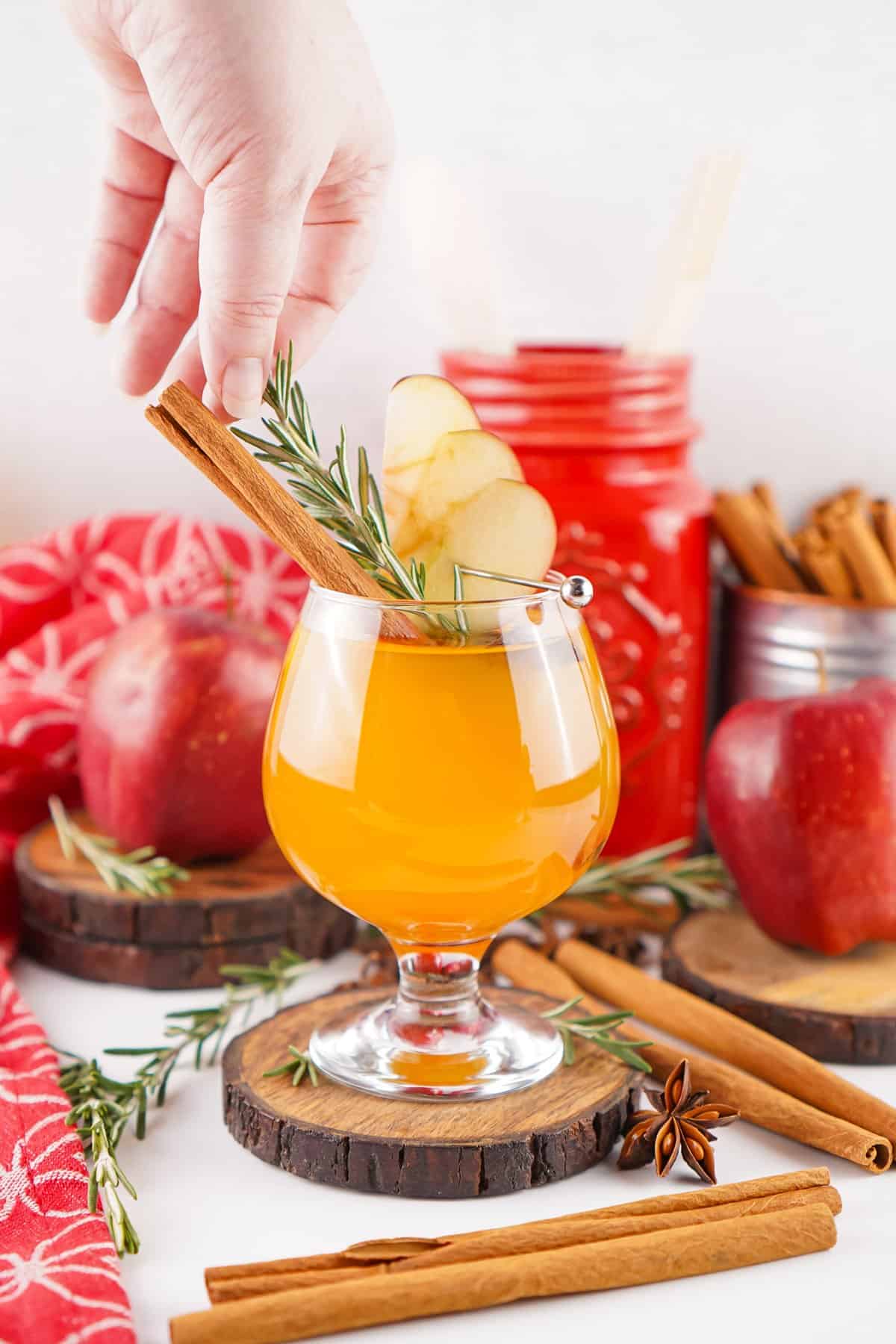 A hand adding garnishes to Fireball apple cider