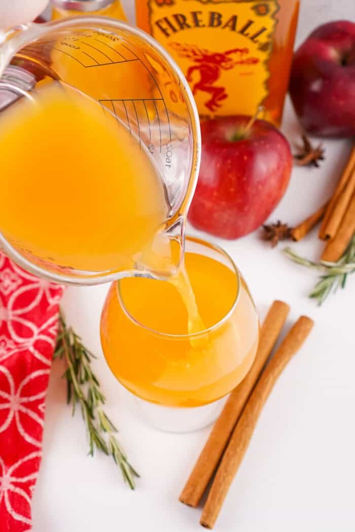 Pouring apple cider into a cocktail glass