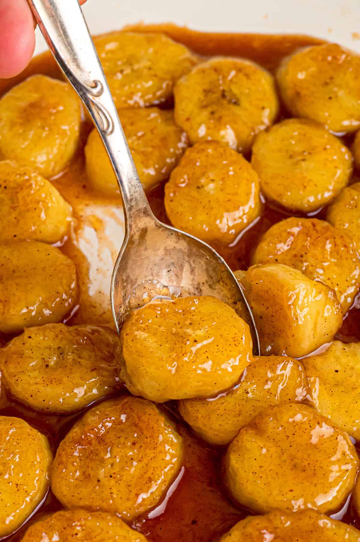 Banana slices are caramelized in a buttery brown sugar sauce in this easy Fried Bananas recipe. Serve over ice cream, pancakes, or waffles. A spoon in a skillet of fried bananas