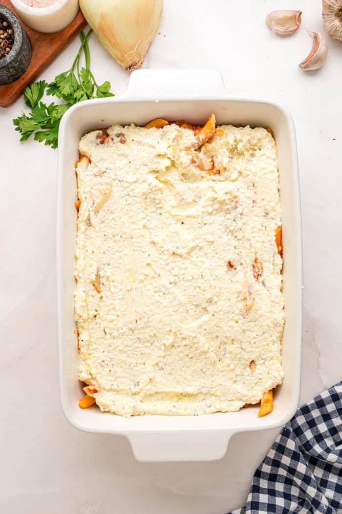 Spreading the ricotta mixture over pasta in a baking dish