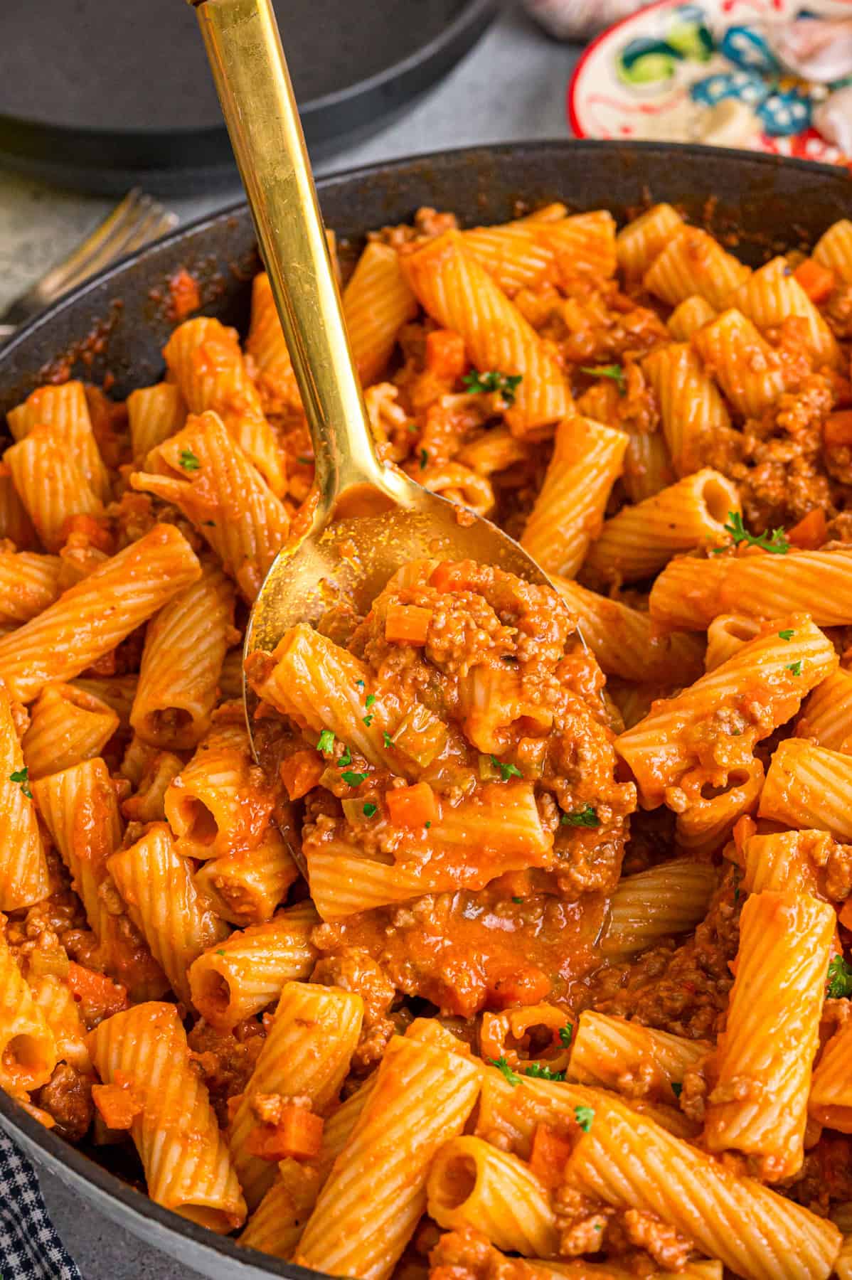 A spoon in a bowl of rigatoni bolognese
