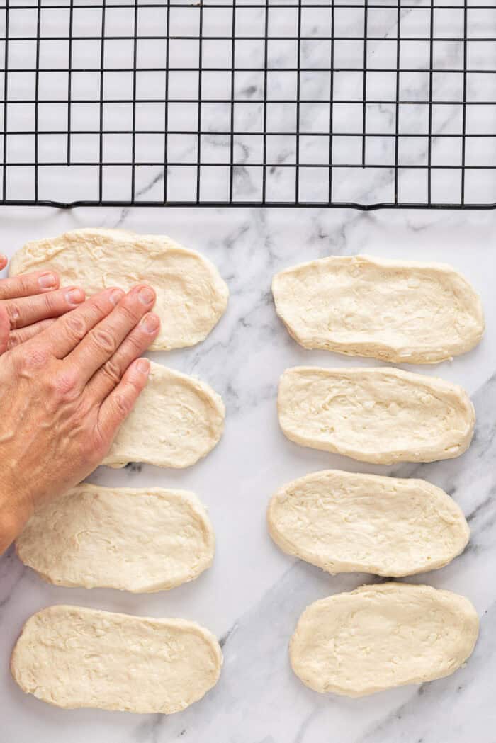 Soft, fluffy fried donuts are topped with a sweet maple frosting in this Maple Bars recipe. Quick & easy to make! Shaping biscuit dough into oblong donuts