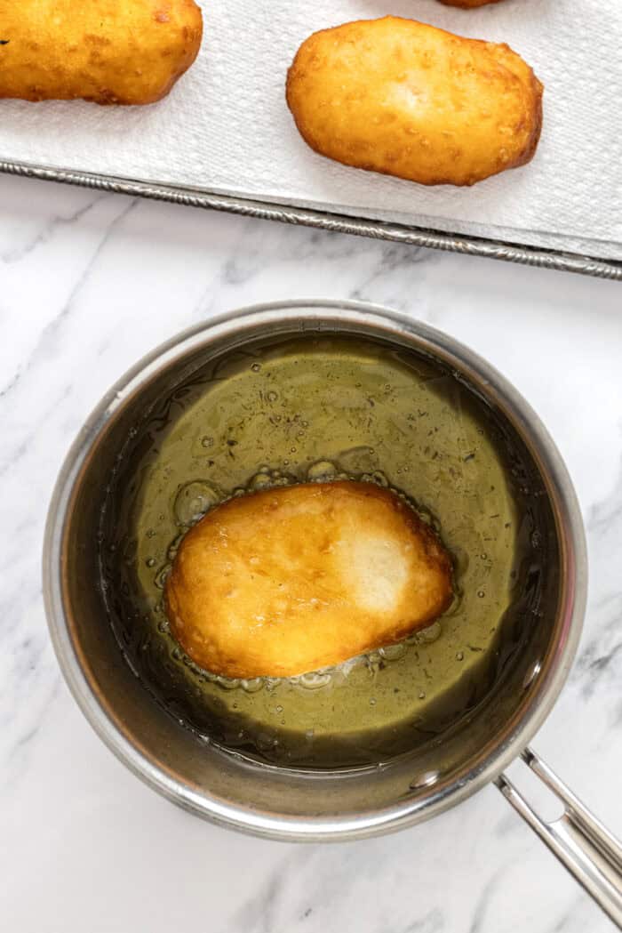 Soft, fluffy fried donuts are topped with a sweet maple frosting in this Maple Bars recipe. Quick & easy to make! Frying biscuit dough in canola oil