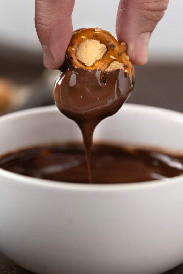 Dipping a peanut butter pretzel bite into melted chocolate