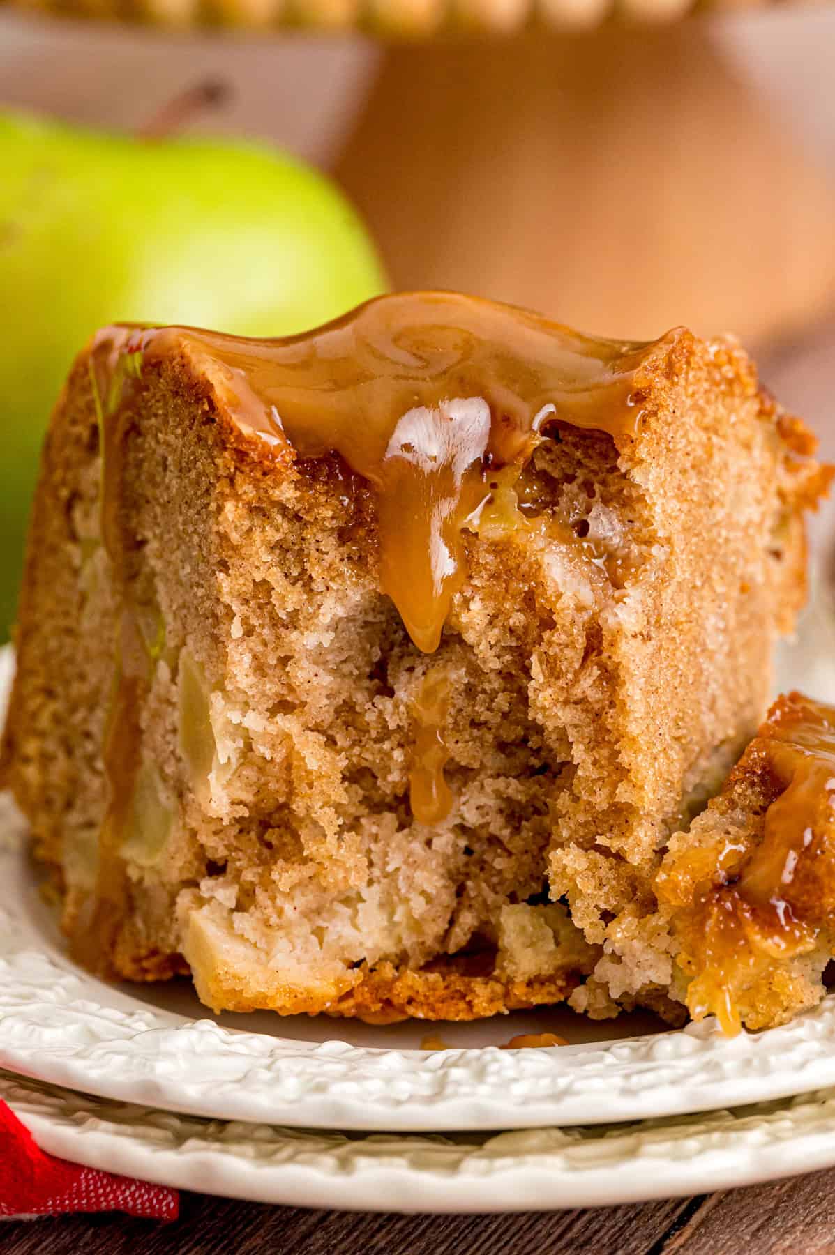 This Apple Bundt Cake is dotted with Granny Smith apples and topped with a sweet caramel glaze. An impressive yet easy fall dessert. A slice of apple bundt cake showing the apple inside