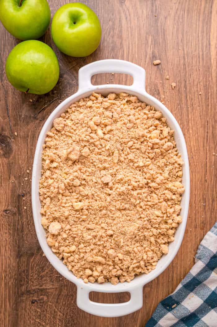 Crumble topping on top of apples in a baking dish