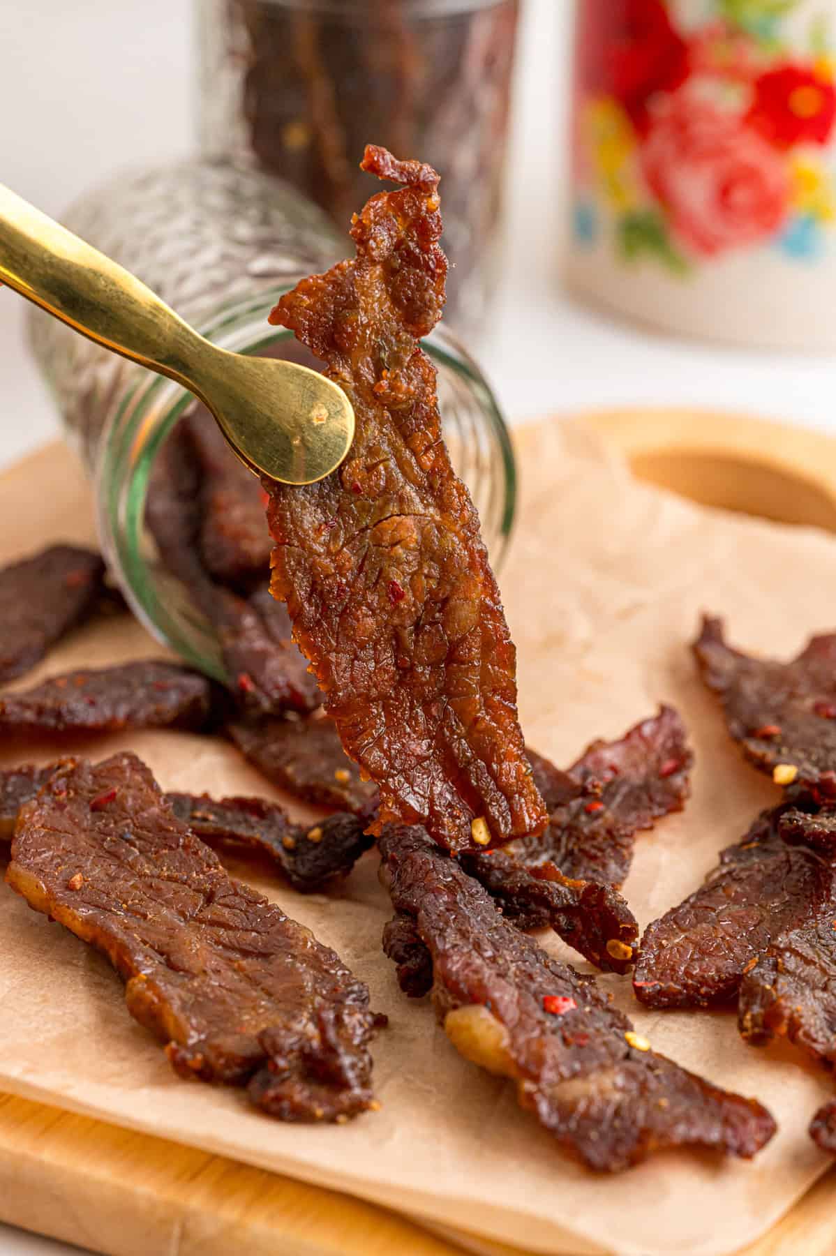Tongs holding a piece of homemade beef jerky