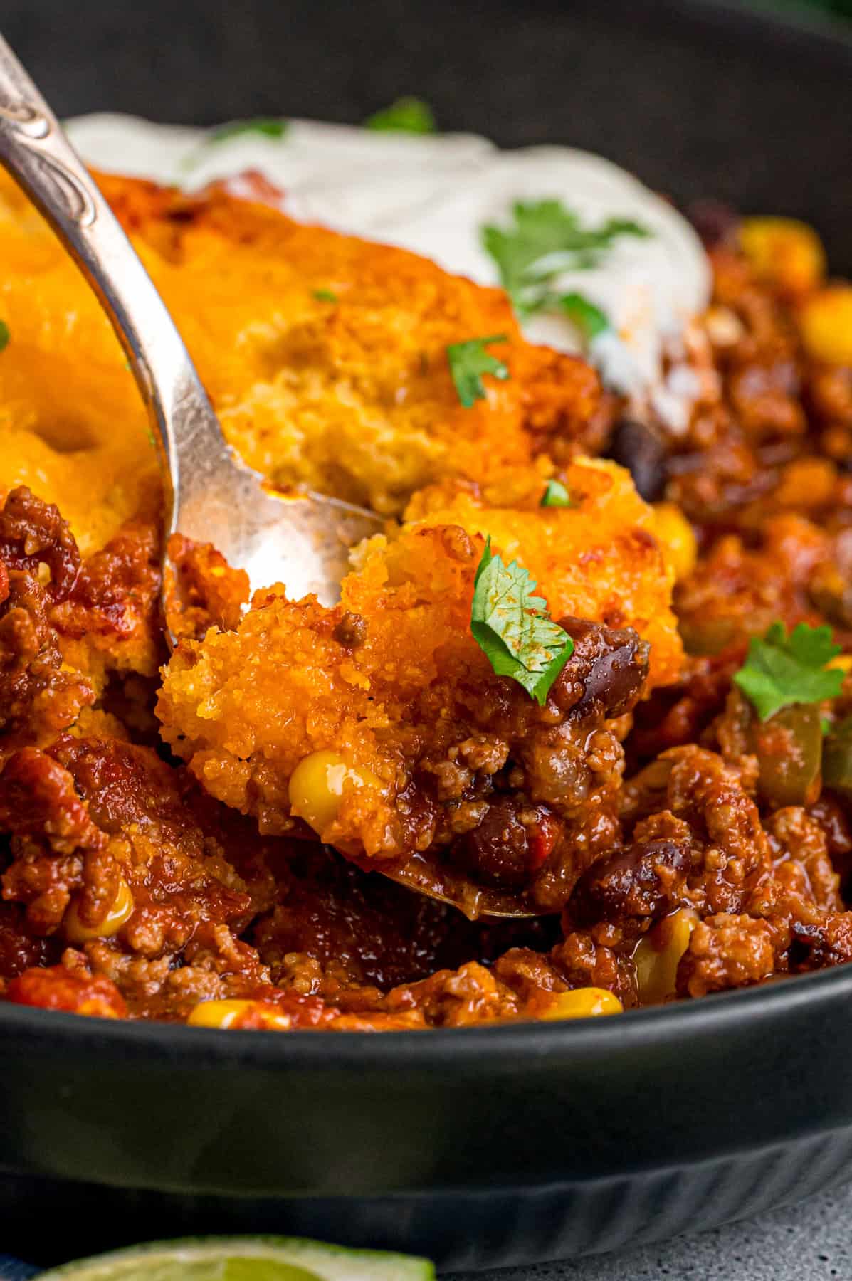 Close up of a spoon on a plate of chili cornbread casserole