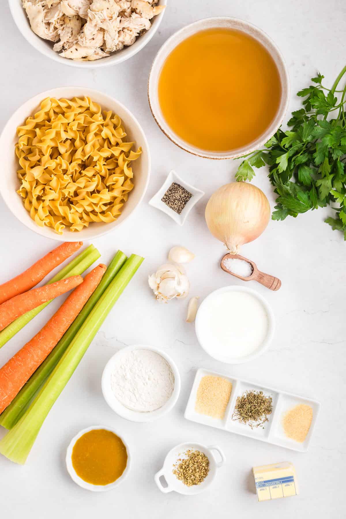 Creamy Chicken Noodle Soup combines tender chicken, hearty noodles, and a flavorful broth in a single pot for a comforting & easy meal. Overhead view of ingredients needed to make creamy chicken noodle soup