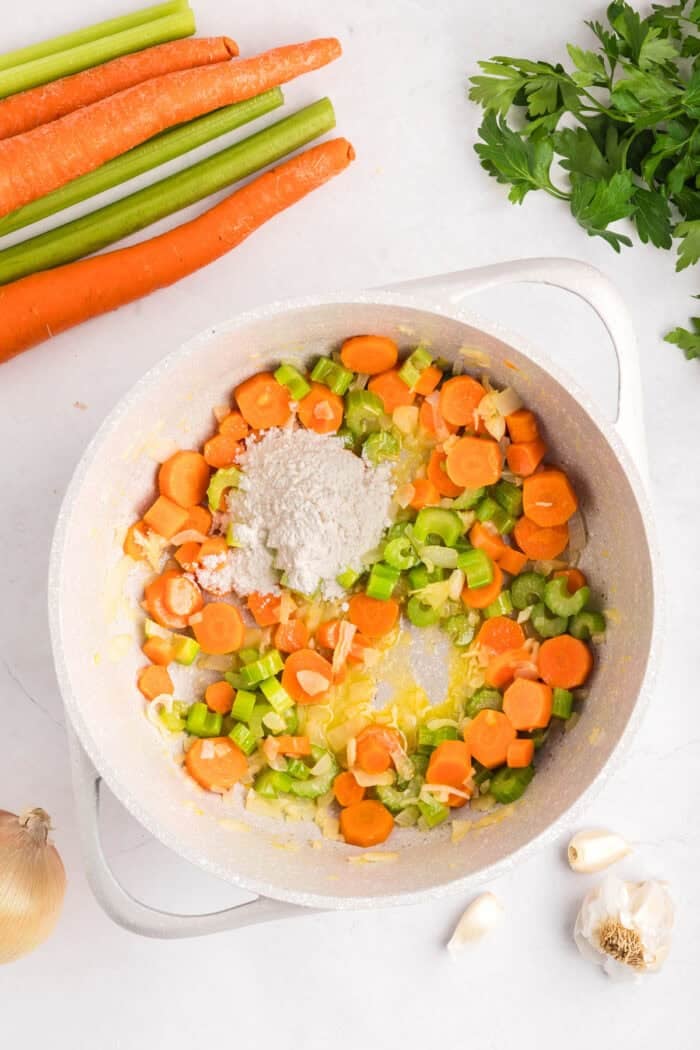 Creamy Chicken Noodle Soup combines tender chicken, hearty noodles, and a flavorful broth in a single pot for a comforting & easy meal. Carrots, onion, and celery in a pot