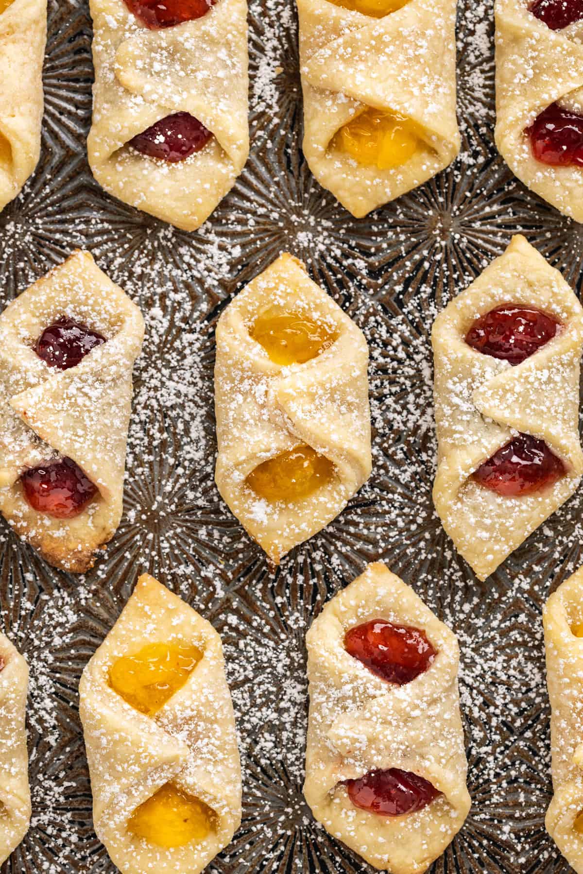 Kolaczki Cookies, aka Polish filled cookies, are made with a simple cream cheese dough and jam filling. They’re simple yet beautiful. Close up of kolaczki cookies dusted with powdered sugar