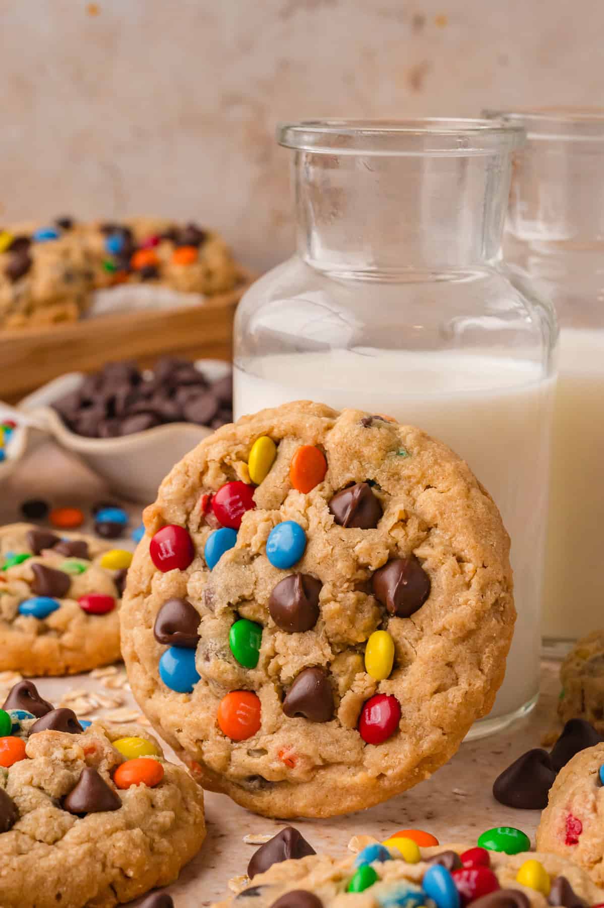 A monster cookie leading against a jar of milk