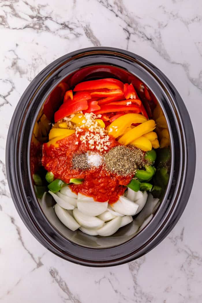Diced bell peppers, onions, marinara sauce, and spices in a slow cooker