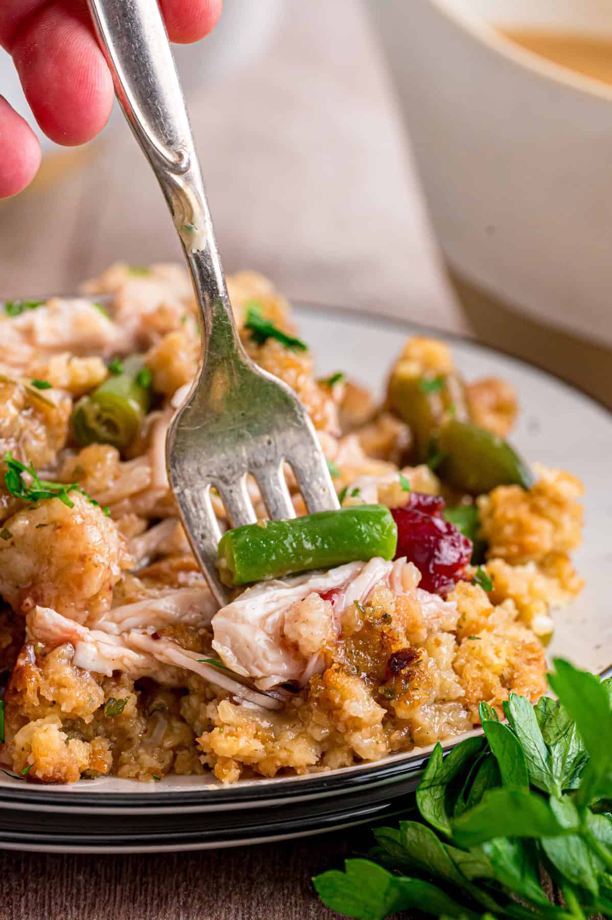 Turkey Stuffing Casserole is an easy way to repurpose Thanksgiving leftovers like turkey, gravy, cranberry sauce, and stuffing. A fork in a plate of turkey stuffing casserole