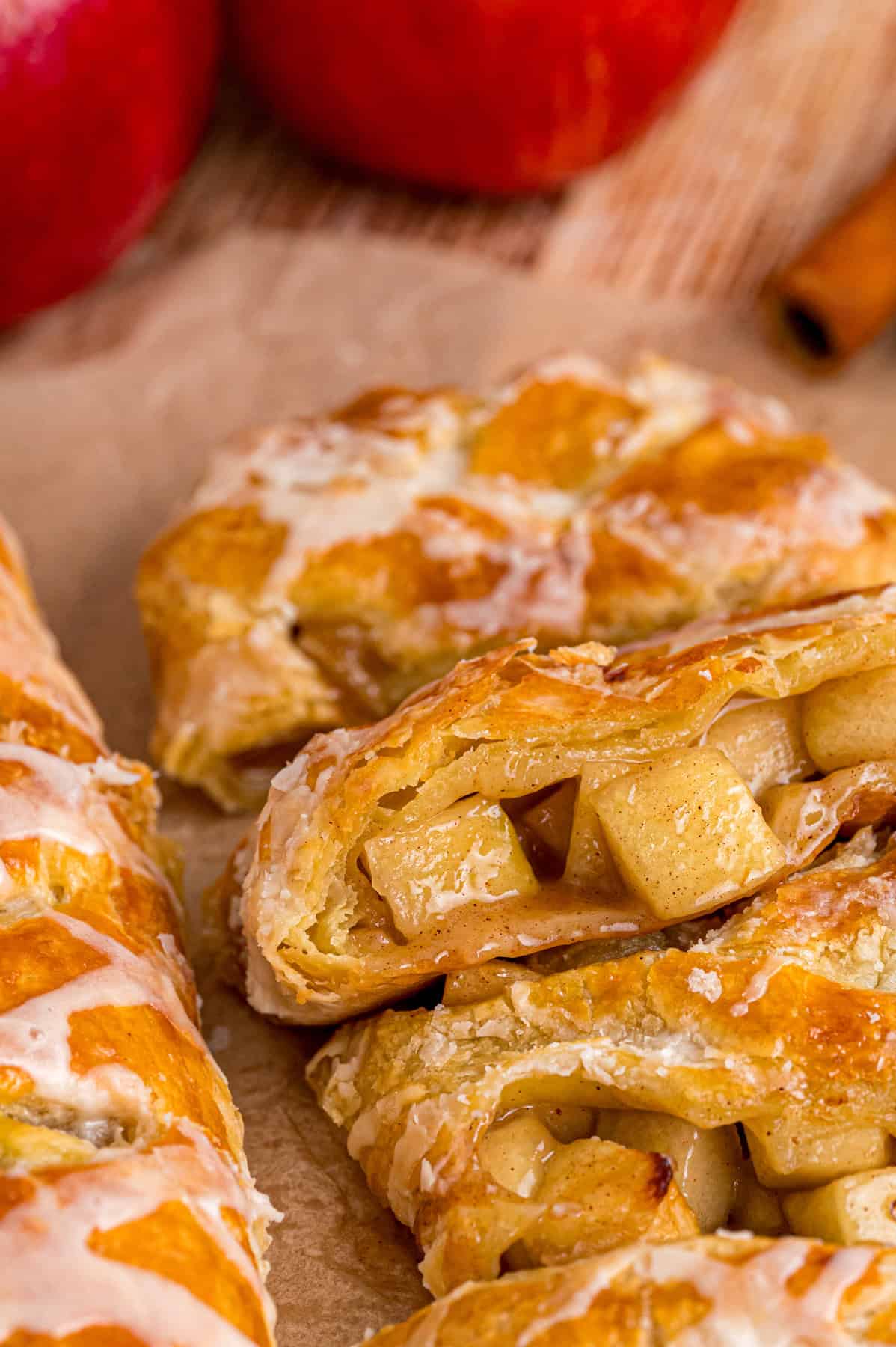 Warmly spiced apple filling is baked inside puff pastry sheets and topped with an irresistible maple glaze in this Apple Strudel recipe. Slices of apple strudel on a cutting board