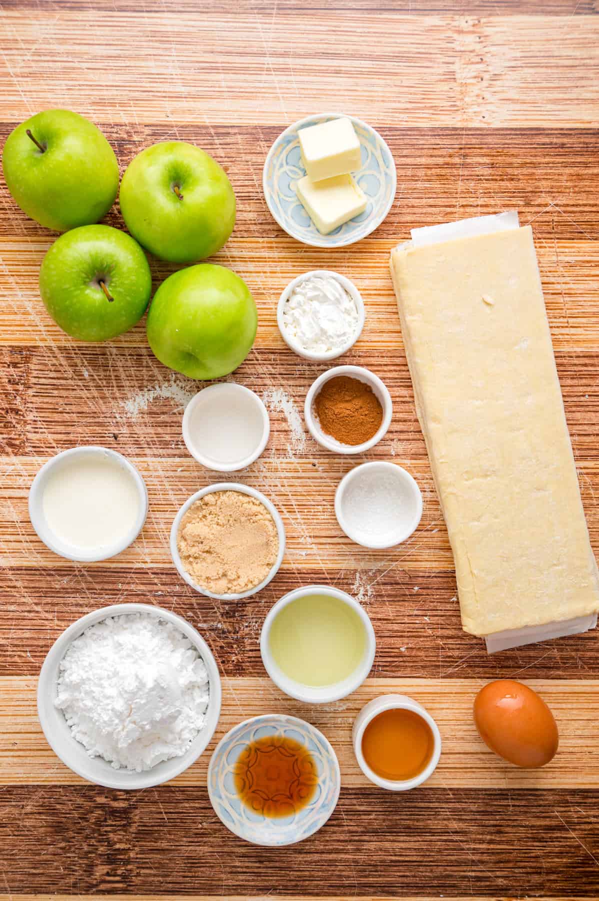 Warmly spiced apple filling is baked inside puff pastry sheets and topped with an irresistible maple glaze in this Apple Strudel recipe. Overhead view of ingredients needed to make apple strudel