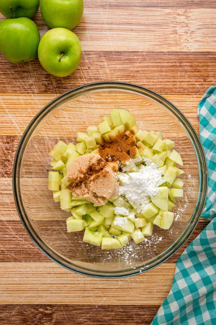 Warmly spiced apple filling is baked inside puff pastry sheets and topped with an irresistible maple glaze in this Apple Strudel recipe. Diced apples, cornstarch, brown sugar, and cinnamon in a bowl