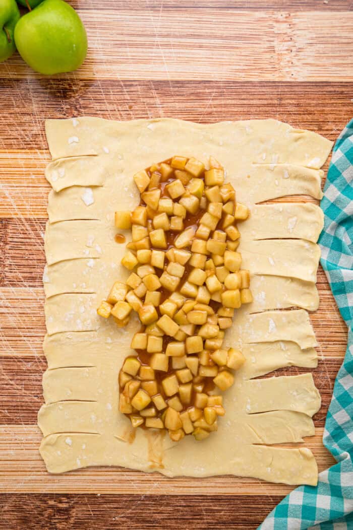 Warmly spiced apple filling is baked inside puff pastry sheets and topped with an irresistible maple glaze in this Apple Strudel recipe. Apple filling on a puff pastry sheet with the edges cut