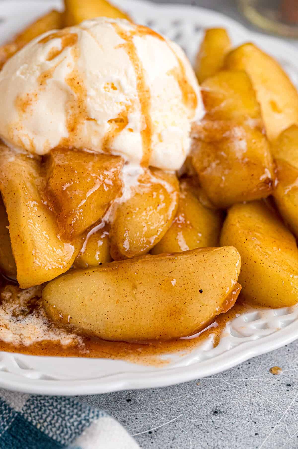 These Southern Fried Apples are warmly spiced, tender, and coated in a yummy brown sugar syrup. Enjoy with ice cream! A bowl of Southern fried apples with ice cream and caramel