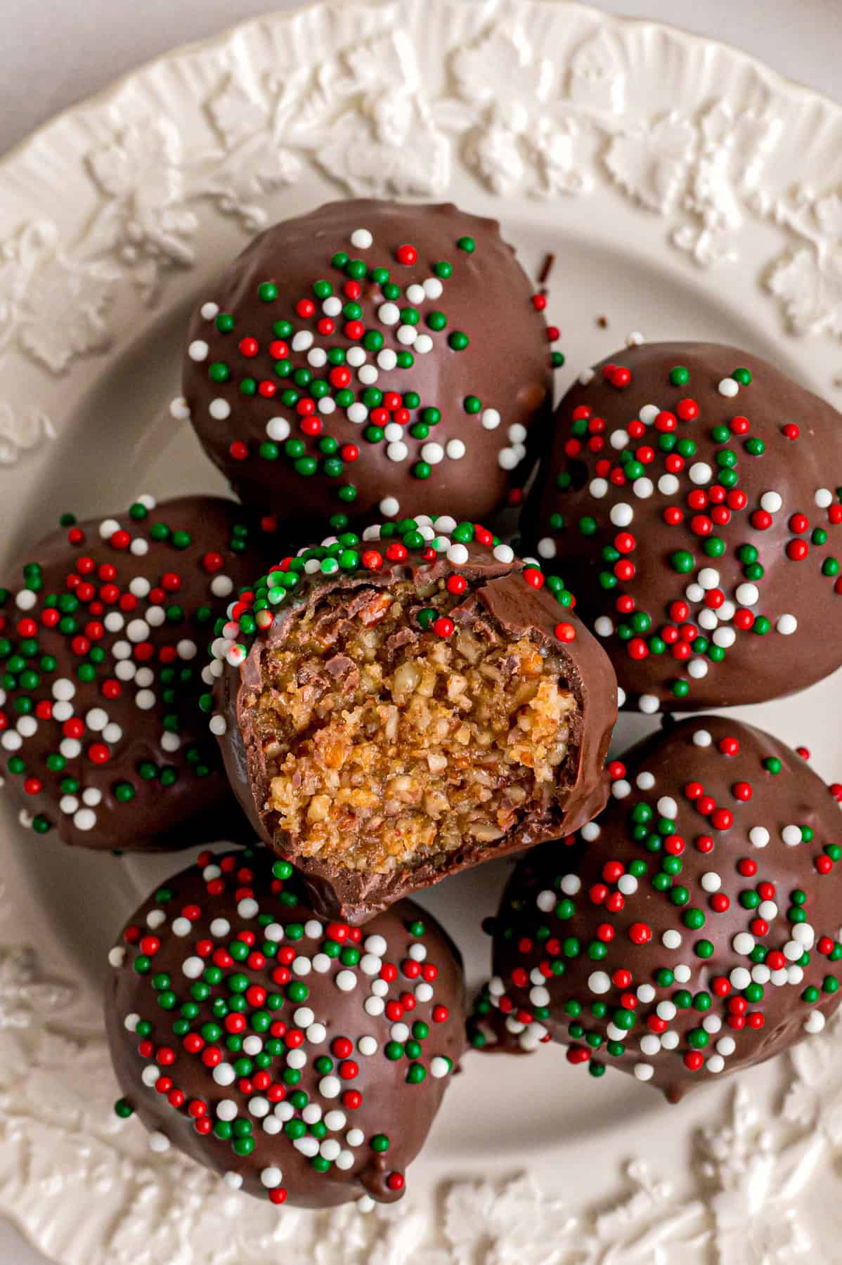 A plate of pecan pie balls, one with a bite missing to show the inside