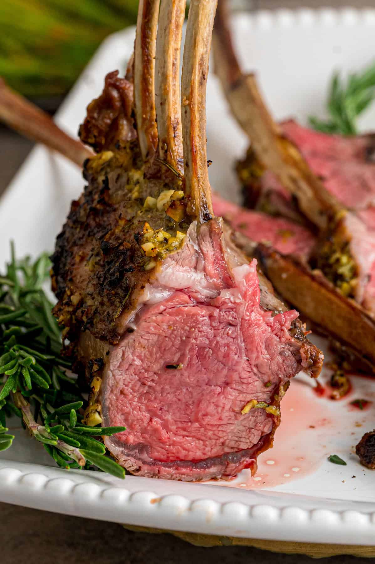 A rack of lamb cooked medium rack on a white serving plate