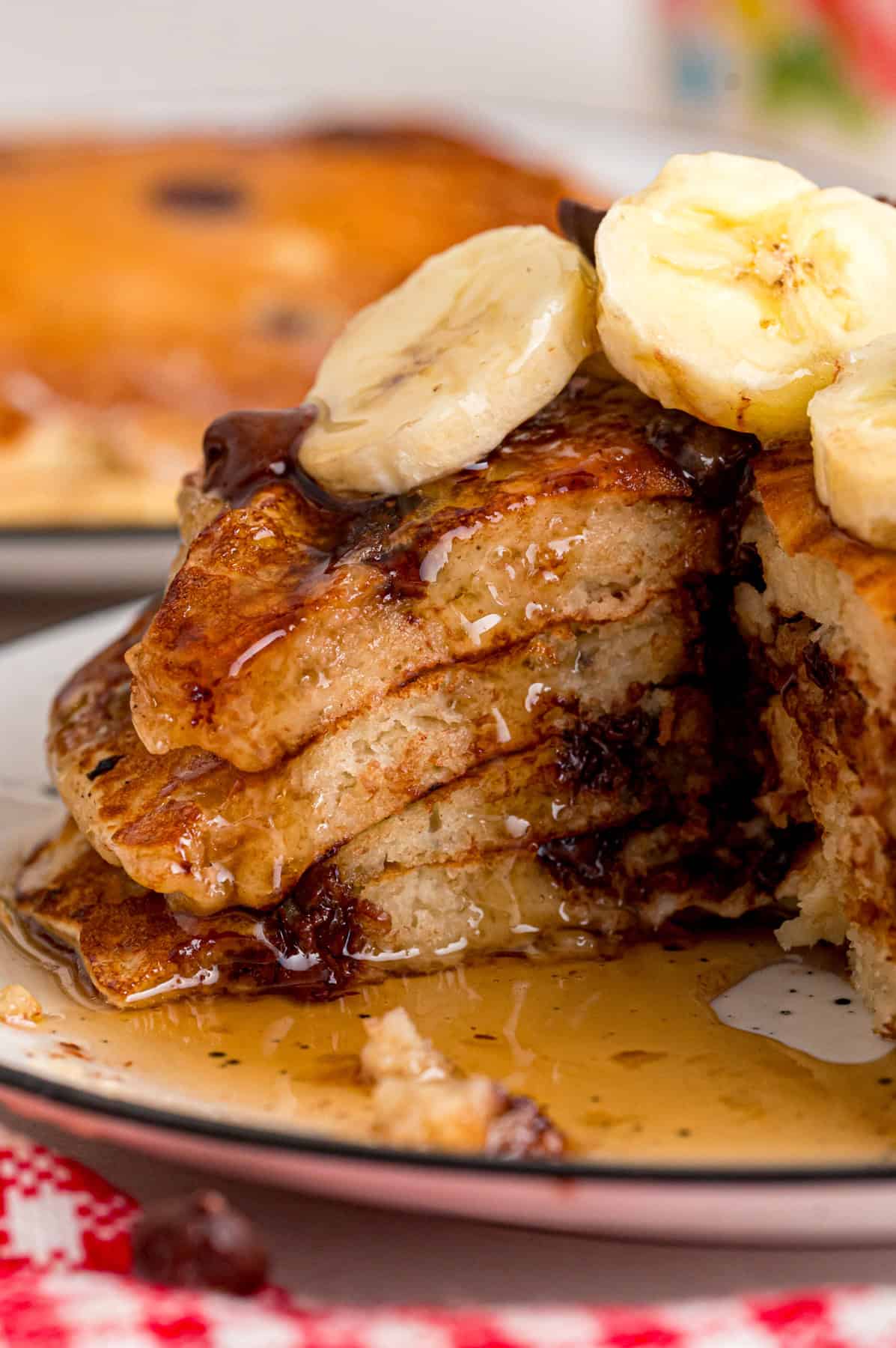 Every bite of these Banana Chocolate Chip Pancakes is dotted with chocolate chips and filled with sweet banana flavor. A stack of banana chocolate chip pancakes with a piece cut out