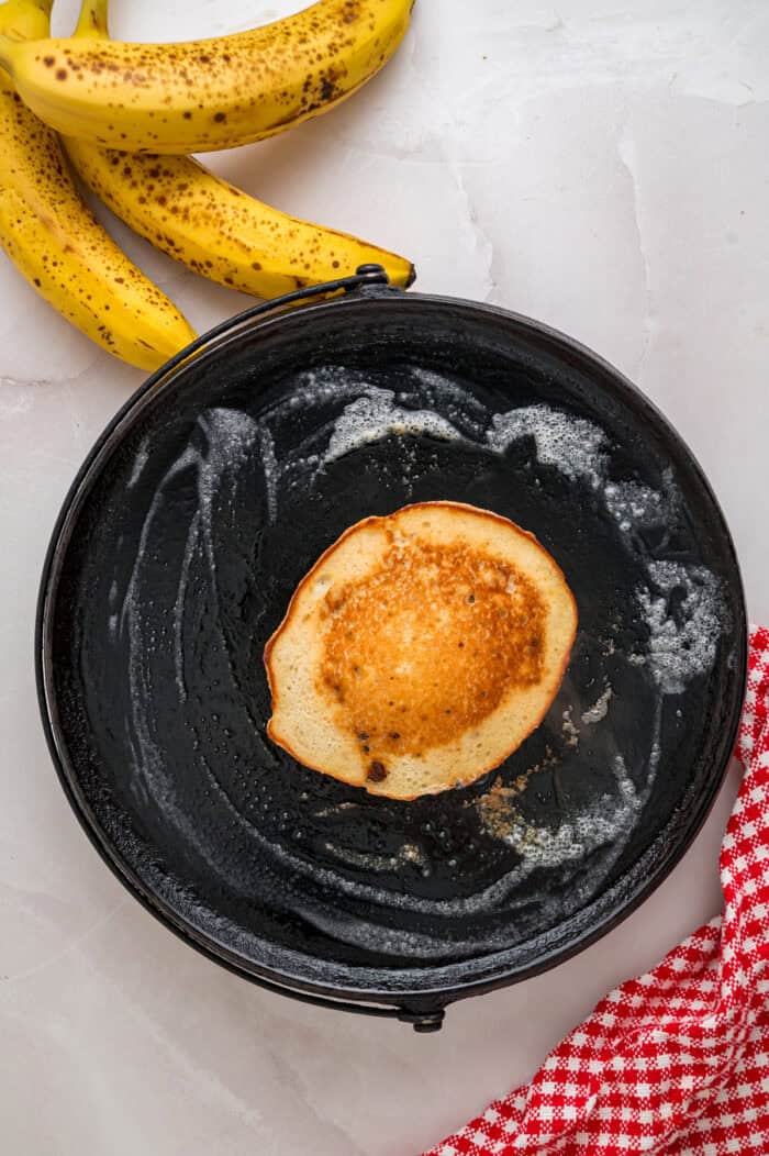 Every bite of these Banana Chocolate Chip Pancakes is dotted with chocolate chips and filled with sweet banana flavor. Overhead view of a banana chocolate chip pancake on a griddle