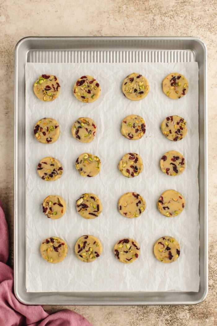 Slices of cranberry pistachio shortbread dough on a baking sheet