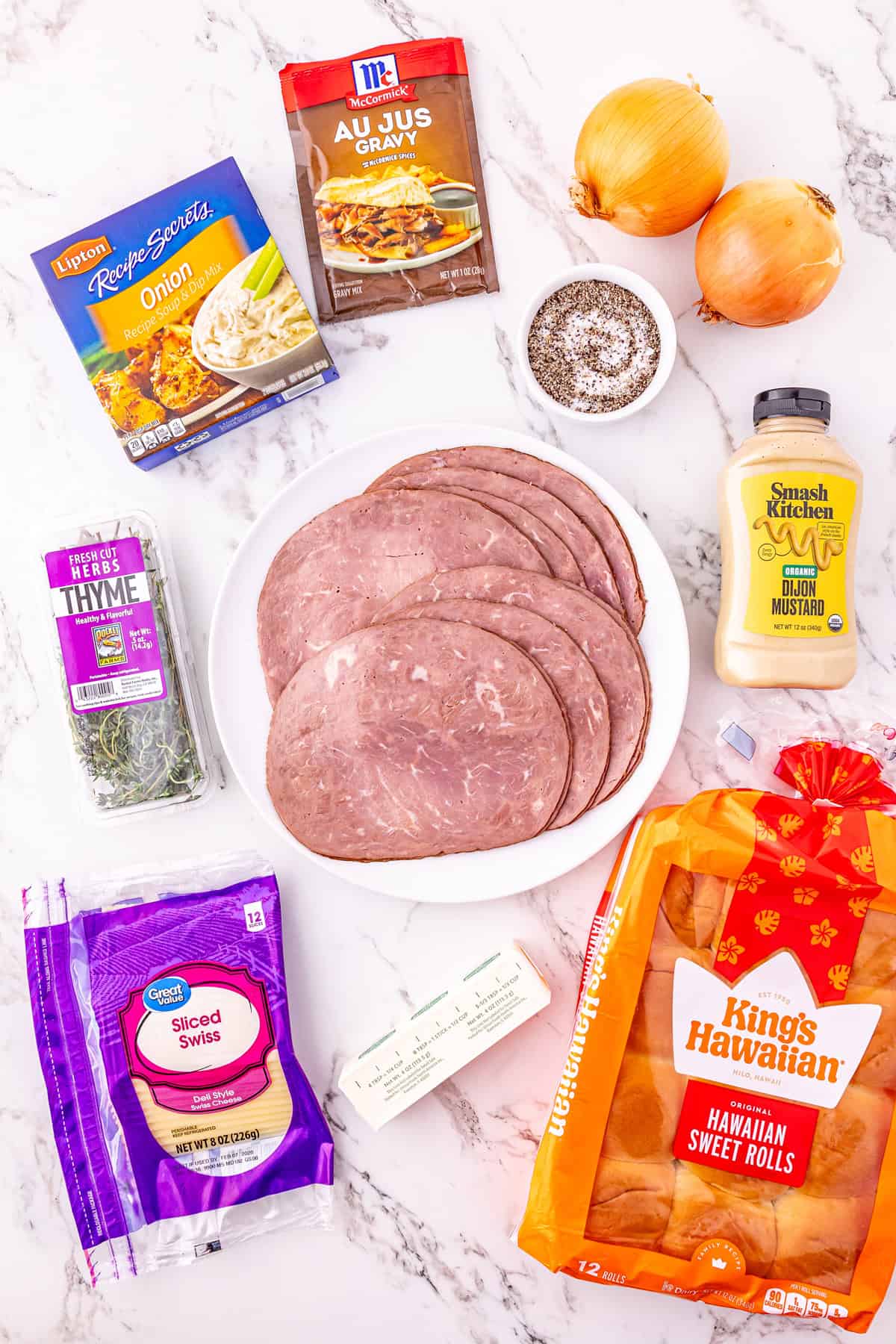 Roast beef, caramelized onions, and Swiss cheese are layered on Hawaiian rolls to make these easy French Dip Sliders. Overhead view of ingredients needed to make French dip sliders