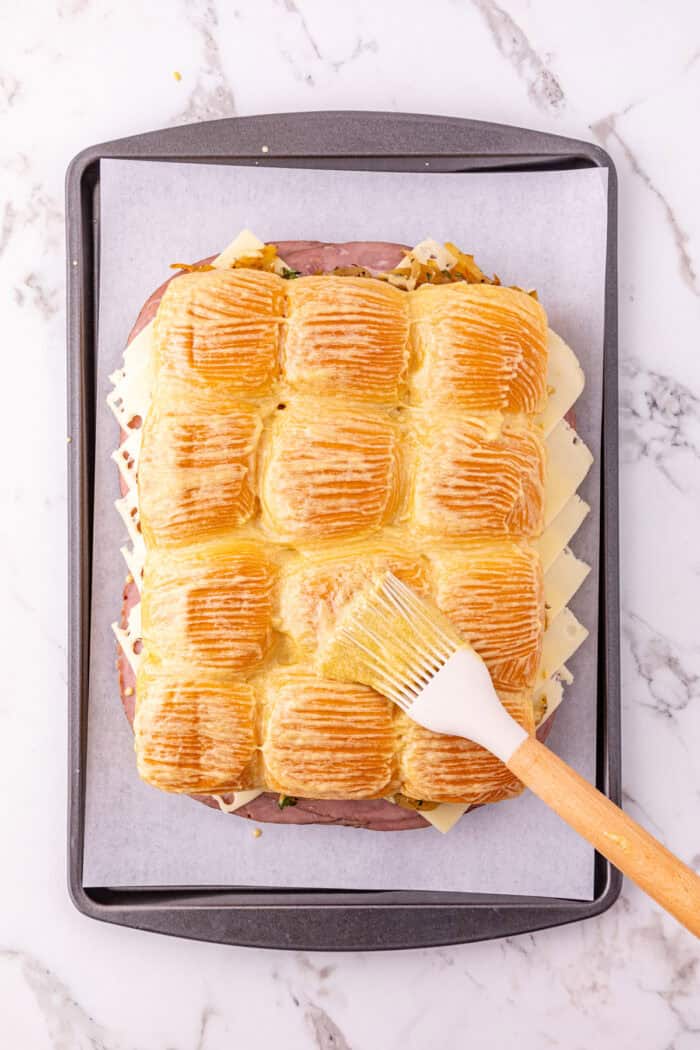 Roast beef, caramelized onions, and Swiss cheese are layered on Hawaiian rolls to make these easy French Dip Sliders. Brushing butter over the tops of sliders