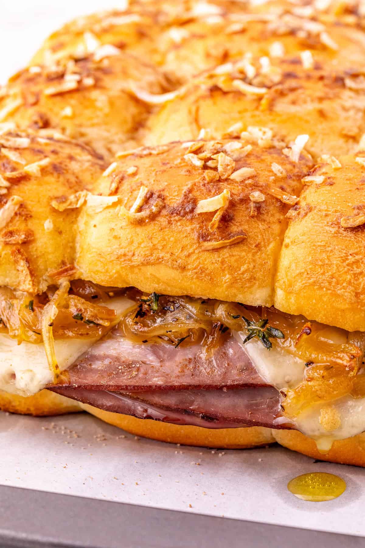 Roast beef, caramelized onions, and Swiss cheese are layered on Hawaiian rolls to make these easy French Dip Sliders. Side view of French dip sliders